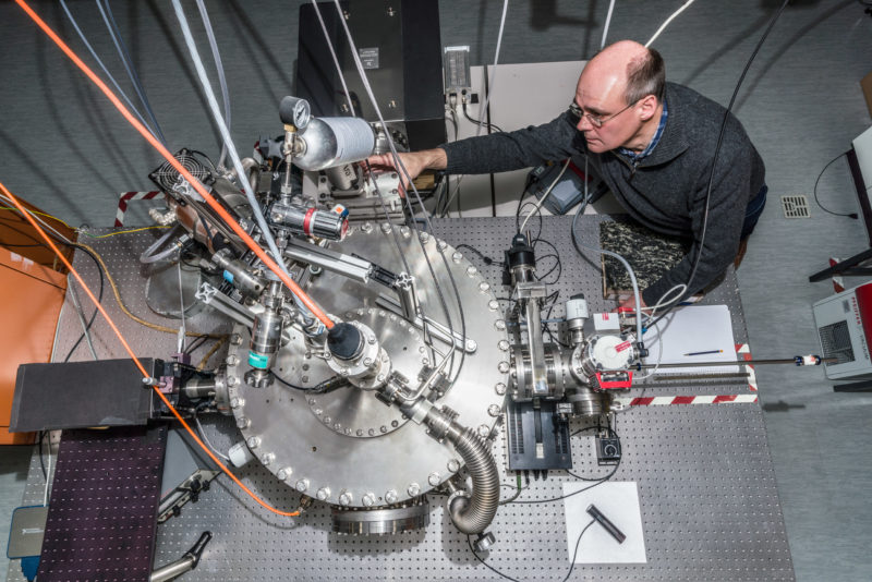 Wissenschaftsfotografie: Von oben fotografierter komplizierter Versuchsaufbau mit Forscher am 3. Physikalischen Institut der Universität Stuttgart.