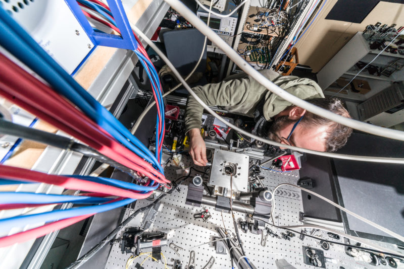 Wissenschaftsfotografie an einem Physikalischen Institut der Universität Stuttgart: Von oben fotografierter komplizierter Versuchsaufbau mit Forscher am 3. Physikalischen Institut der Universität Stuttgart.