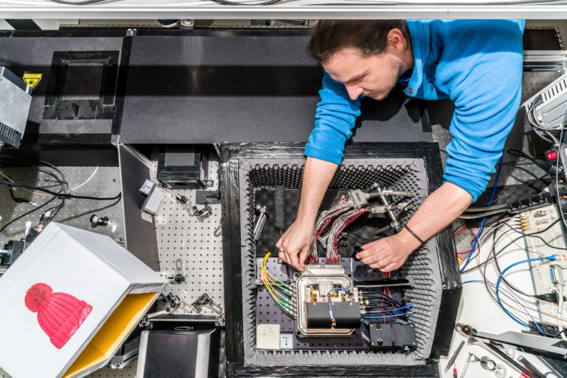 Wissenschaftsfotografie an einem Physikalischen Institut der Universität Stuttgart: Von oben fotografierter komplizierter Versuchsaufbau mit Forscher am 3. Physikalischen Institut der Universität Stuttgart.