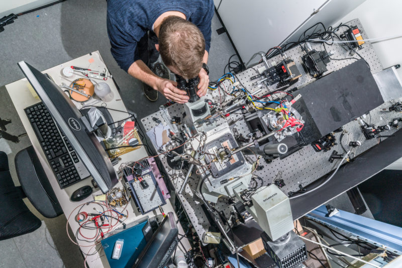 Science photography: Complicated experimental set-up photographed from above with researchers at the 3rd Institute of Physics at the University of Stuttgart.