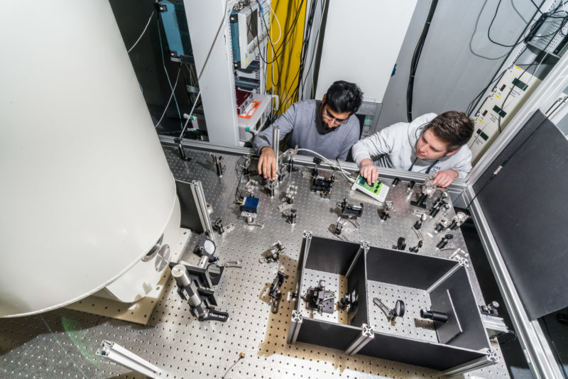 Wissenschaftsfotografie: Von oben fotografierter komplizierter Versuchsaufbau mit Forscher am 3. Physikalischen Institut der Universität Stuttgart.