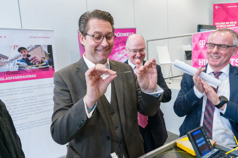 Eventfotografie, Veranstaltungsfotografie Reportagefotografie: Anlässlich einer Vertragsunterzeichnung für den Breitband-Internet-Netzausbau lässt sich Bundesverkehrsminister Andreas Scheuer das Schweissen von Glasfaserkabeln erklären. Er hält das fertig verbundene Faserstück in die Höhe, während Achim Bothe von der Deutschen Telekom AG und Landrat Wolf-Rüdiger Michel Beifall klatschen.