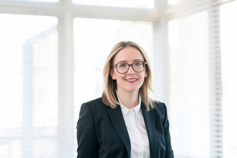 Managerportrait: A colleague from a law firm in a brightly lit conference room. She wears large glasses and despite the illumination with a flash system there are no reflections in the lens.