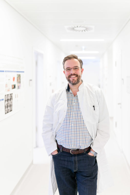 Portrait eines Augenarztes im Flur des Forschungsinstituts an einer Universitätsklinik.