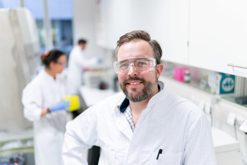 Portrait of an ophthalmologist at a university hospital: Here he is standing in the laboratory with a lab coat and protective goggles.