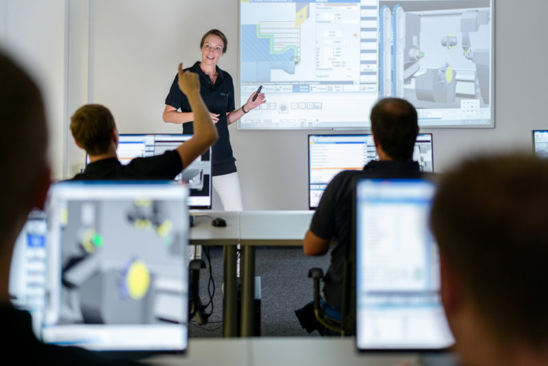 Industrial photography: Editorial photography: A trainer with employees during a technical training in a company. The computer screens and the projection on the blackboard light up.