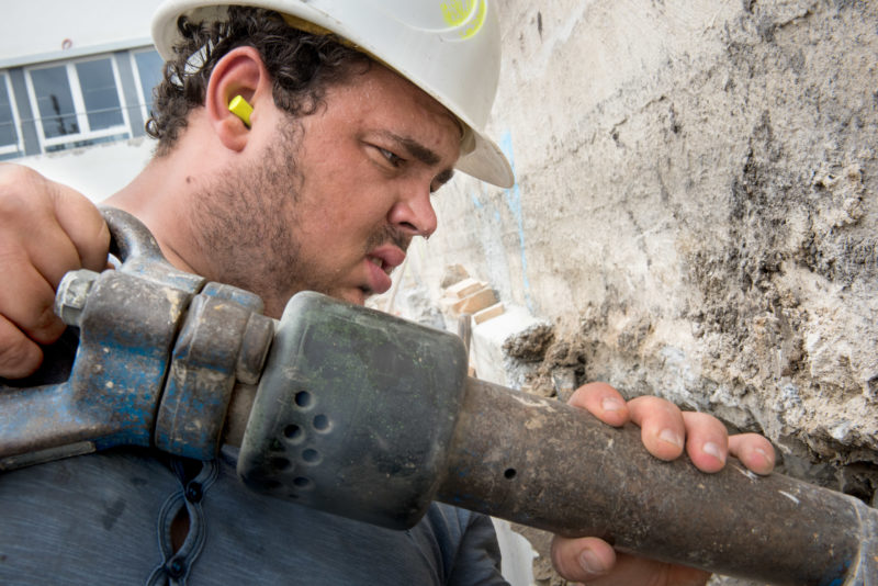 Editorial photography: A construction worker has drops of sweat on the tip of his nose when working with the pneumatic hammer.