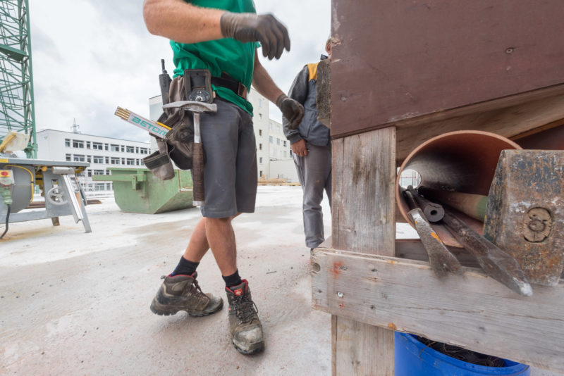 Reportagefotografie: Bauarbeiter mit Werkzeuggürtel. Darin befinden sich Hammer, Funkgerät und Massstab.