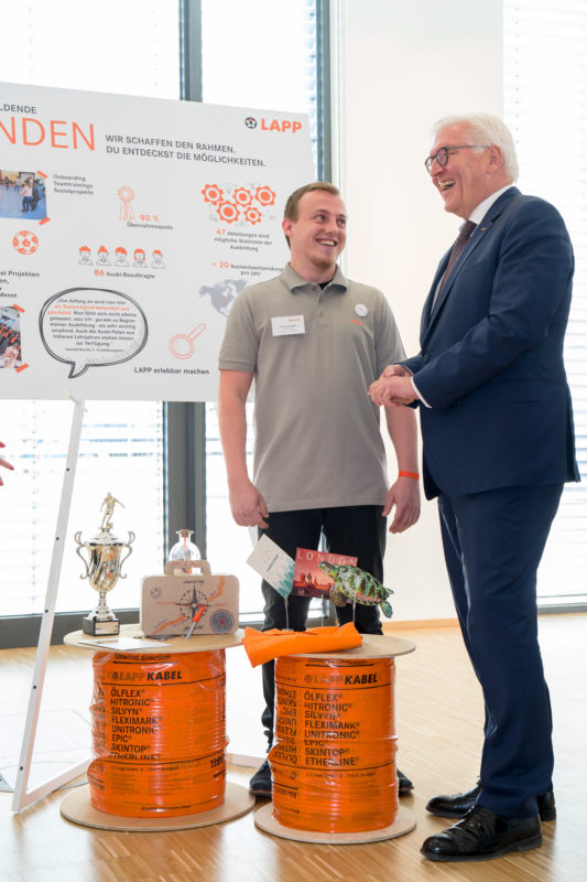 Eventfotografie, Reportagefotografie: Besuch des Bundespräsidenten Frank-Walter Steinmeier der Firma Lapp Kabel in Stuttgart. Bei der Unterhaltung mit einem der Auszubildenden lacht der Bundespräsident.