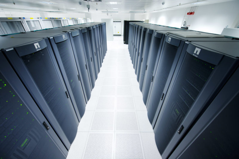 Industrial photography:  In a data center there are a large number of black server racks in two rows.