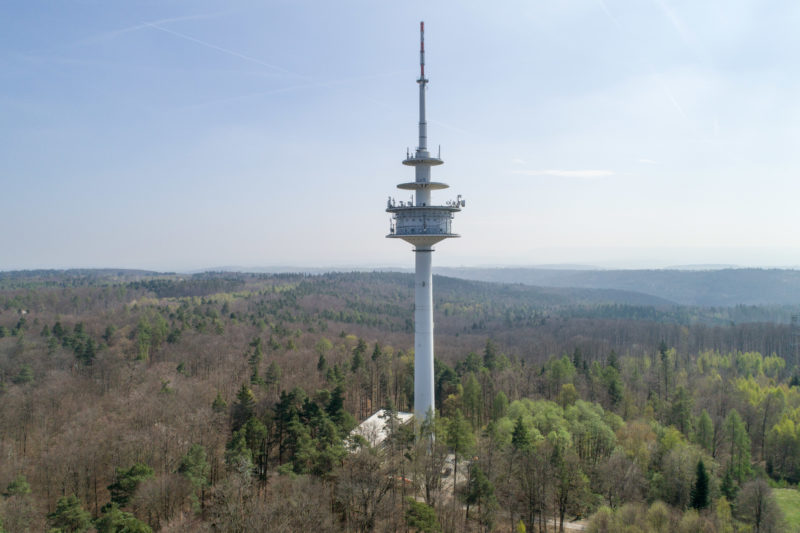 Luftaufnahmen und Drohnenfotografie: Ein Funkturm in der bewaldeten sanften Hügellandschaft der schwäbischen Alb.