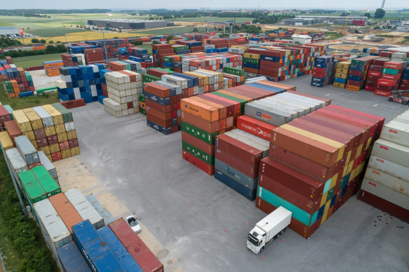 Aerial and Drone photography: A white truck in a test of a positioning system within a container warehouse.