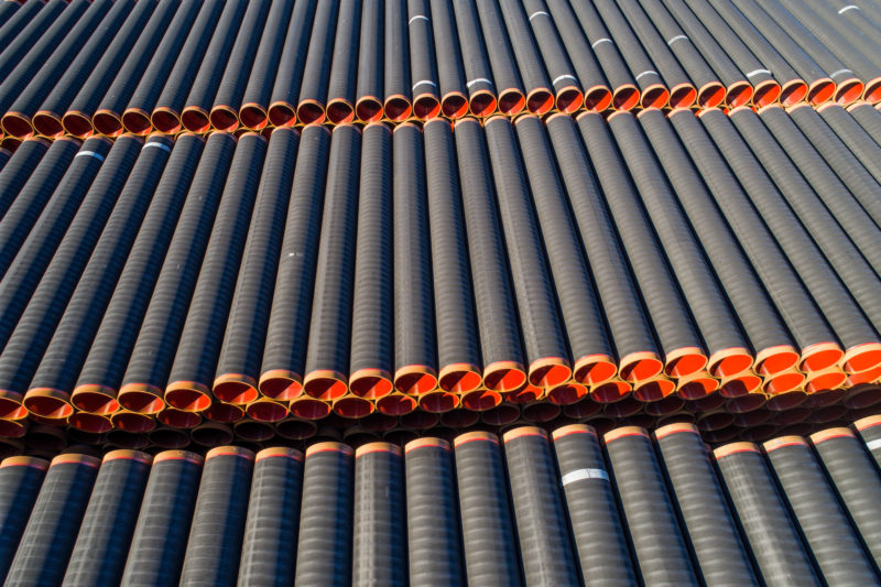 Aerial and Drone photography: Pipes for a pipeline under construction are stacked in a large outdoor storage facility.