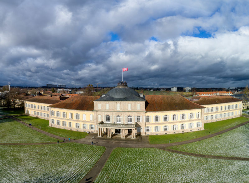 Aerial and Drone photography: The castle of the University of Hohenheim as a panoramic view. A flag is hoisted on the dome of the main building.