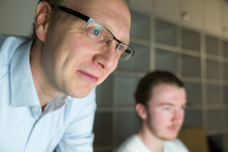 Editorial Fotografie: Wissenschaftler forscht an der Schnittstelle zwischen Mensch und Maschine und der dafür notwendigen visuellen Interaktion. Bei diesem nahen Portrait ist der Fokus der Kamera auf den Augen des Wissenschaftlers als er sich über ein Notebook beugt.