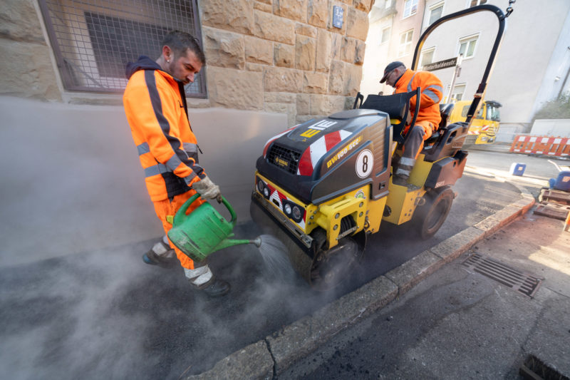 Reportage photography on a fiber optic construction site: To lay lines for fast Internet in an urban residential area, the sidewalk was opened and is now being tarred again.