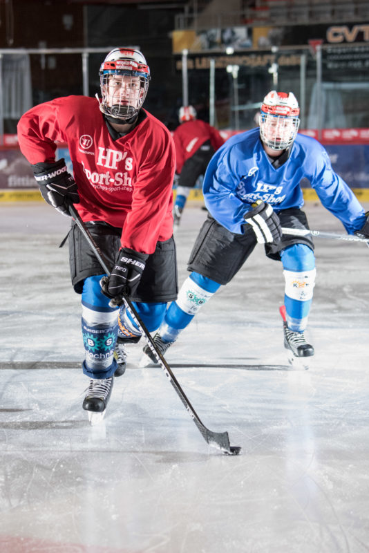 Employees photography: A young man playing ice hockey. In the background one of the pursuers of the opposing team.