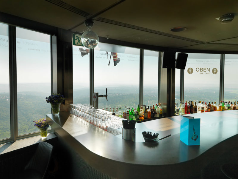 Reportagefotografie: Übung der Feuerwehr-Höhenretter am Stuttgarter Fernsehturm. Von der Bar im Turm aus sieht man vor dem Fenster die Stiefel eines sich aus ca. 180 Metern Höhe abseilenden Retters.