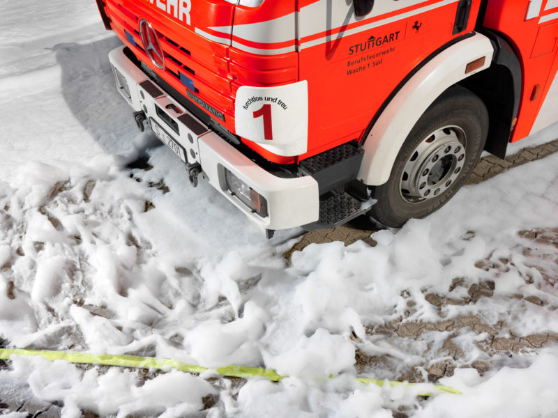 editorial photography: Around a fire engine, white fire foam is spread on the floor.