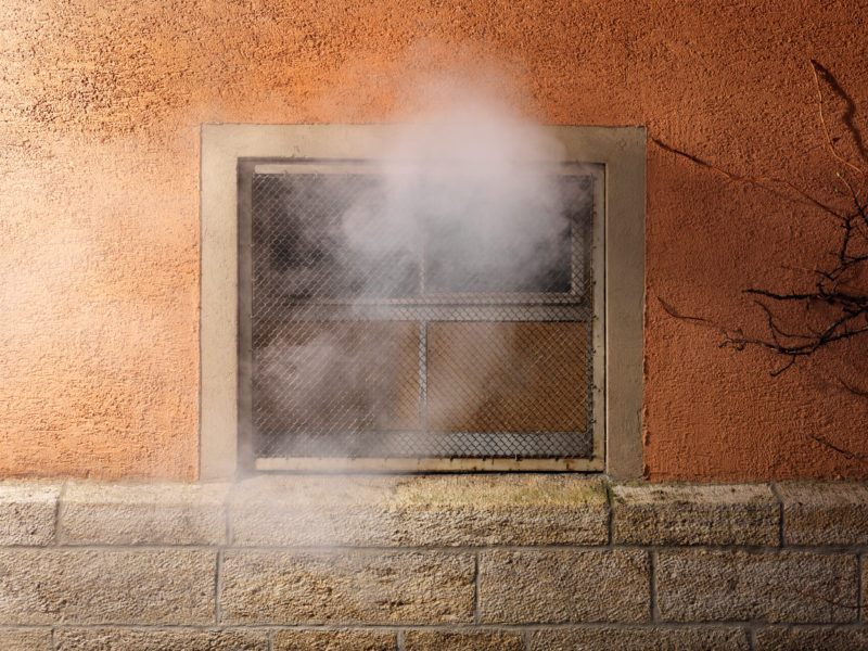 editorial photography: A basement window through which smoke is pouring. Such scenes are often seen by firefighters on arrival at a scene.