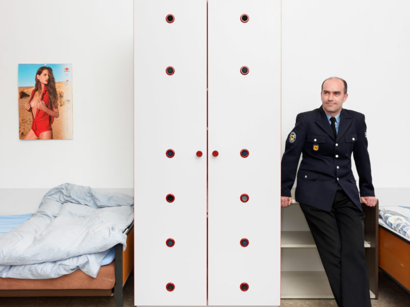 editorial photography: A firefighter in uniform in one of the dormitories of the fire station. The 24-hour shifts mean that the beds are used by several officers.