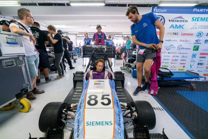 Reportagefotografie: Formula Student Germany: Einer der teilnehmenden Elektrorennwagen in der Box. Der Fahrer sitzt im Cockpit bereitet sich auf die kommende Fahrt vor.