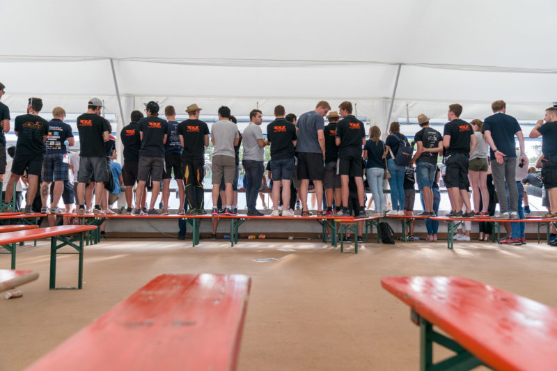 Reportagefotografie: Formula Student Germany: Die meisten Teammitglieder sind Männer. Trotzdem sind auch einige Frauen unter den Zuschauern. Viele stehen auf Bänken, um besser zu sehen.