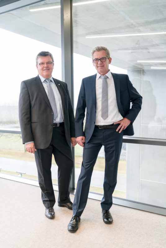 Managerportrait: Two male executives, perfectly dressed in suits and both with gray tie. It