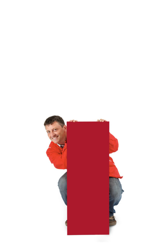Employees photography: For a personnel campaign of a vehicle manufacturer, employees pose with a red sign against a white background. The photos are full body shots and each person acts differently in front of the camera. Here an employee in a red work jacket hides himself behind the sign.