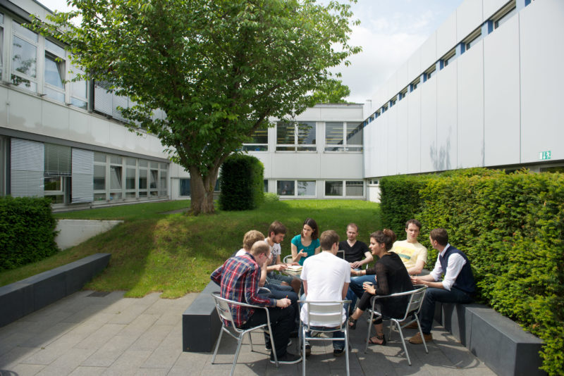 Science photography:  In a garden of the Max Planck Institute for Intelligent Systems, scientists discuss while sitting around a table.