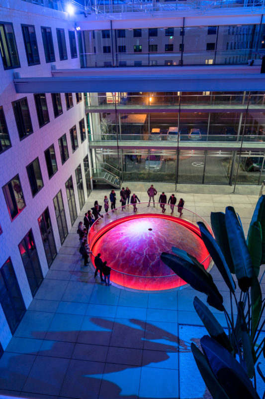 Architectural photography:  Interior view of the Fraunhofer Institute for Industrial Mathematics ITWM in Kaiserslautern. In the roofed atrium, visitors can stow the illuminated dome of the RODOS vehicle simulator in the basement below.