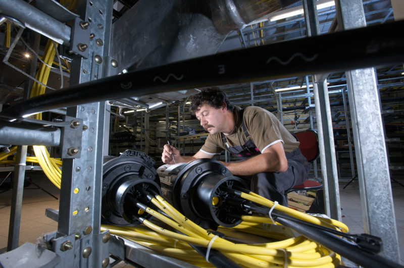 Industrial photography: A technician connects fiber optic cable lines in a switching exchange.