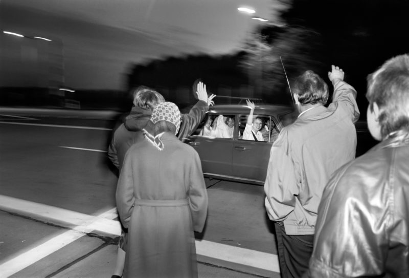 Reportagefotografie DDR Grenzöffnung 1989: Fahrzeuge aus der DDR fahren über die offene Grenze am Grenzübergang Helmstedt/Marienborn und werden von winkenden Westdeutschen begrüßt.