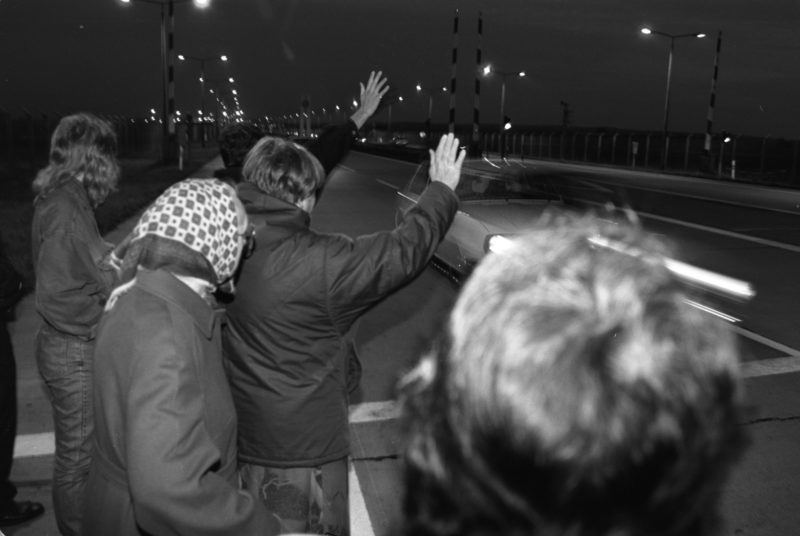 Reportagefotografie DDR Grenzöffnung 1989: Fahrzeuge aus der DDR fahren über die offene Grenze am Grenzübergang Helmstedt/Marienborn und werden von winkenden Westdeutschen begrüßt.