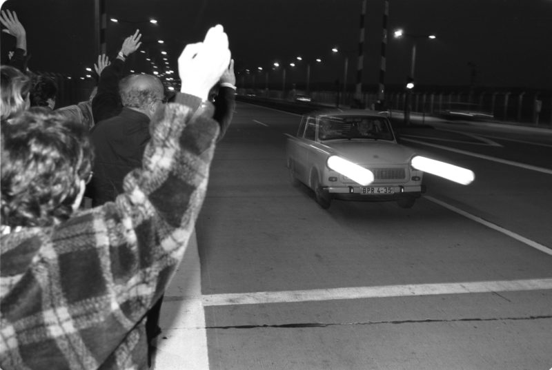 Reportagefotografie DDR Grenzöffnung 1989: Fahrzeuge aus der DDR fahren über die offene Grenze am Grenzübergang Helmstedt/Marienborn und werden von winkenden Westdeutschen begrüßt.