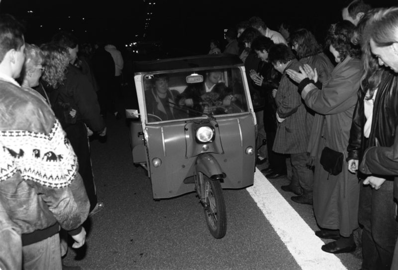 Reportagefotografie DDR Grenzöffnung 1989: Fahrzeuge aus der DDR fahren über die offene Grenze am Grenzübergang Helmstedt/Marienborn und werden von winkenden Westdeutschen begrüßt.