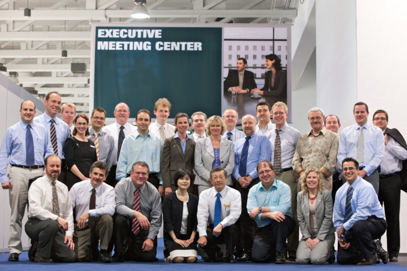 Gruppenfoto: Während einer internationalen Firmenmesse stehen die zahlreichen Teilnehmer eines Fortbildungsseminars zu einem Gruppenfoto zusammen.