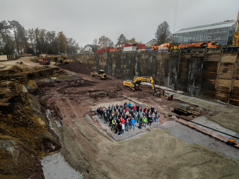 Group photo: On the occasion of the start of construction of a new research building, the future employees there pose for a group picture on the first base plate of the building complex. They almost get lost inside the huge and deep excavation pit.