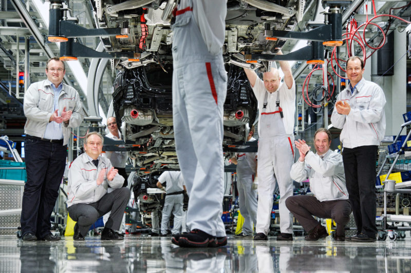 Gruppenfoto: Eine Gruppe Ingenieure am Fließband in der Fahrzeugfertigung.