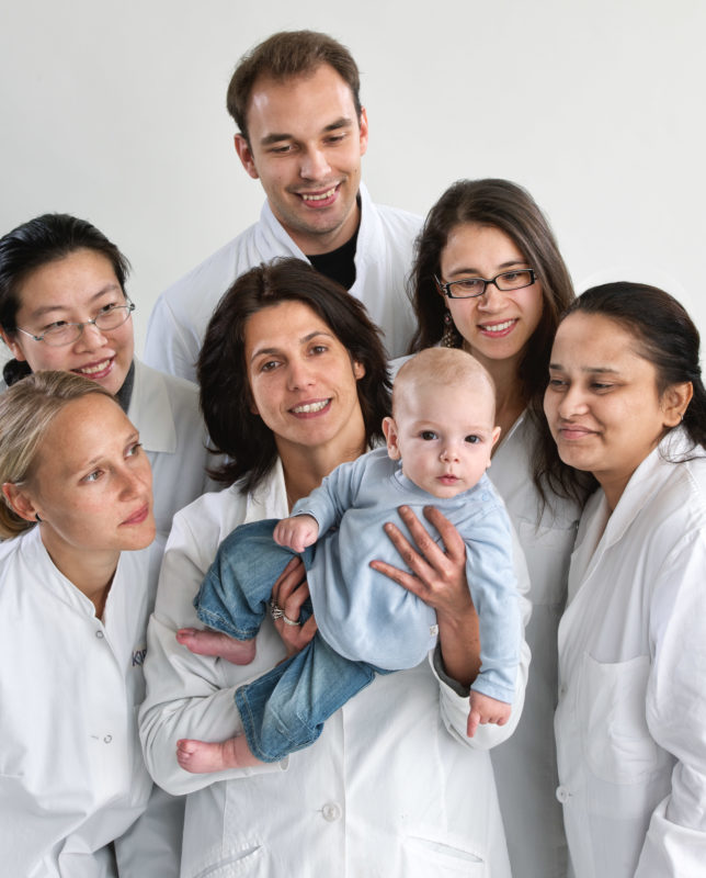 Group photo: Employees Portrait: A group photo of scientists with a baby as a young researcher. Taken on-location with a flash system.