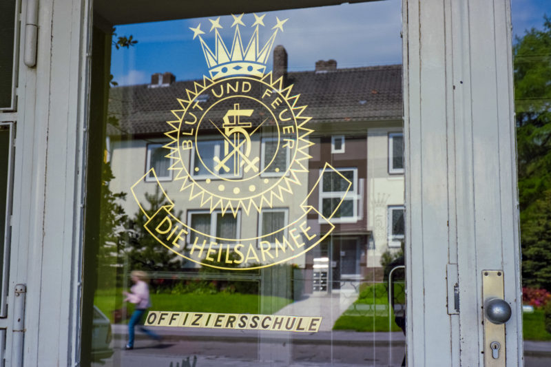 Reportagefotografie bei der Heilsarmee: Eingangstür zur Offiziersschule der Heilsarmee. Ein goldenes Wappen ist auf dem Glas.