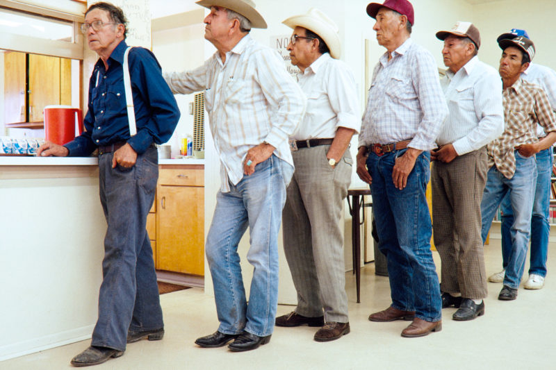 Reportage photography on slide film in the Pine Ridge Reservation in South Dakota, USA: Older Indians queue up at the food counter in the community hall.