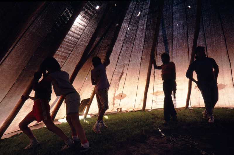 Reportage photography on slide film in the Pine Ridge Reservation in South Dakota, USA: Children help to build a big tent in which a sweating ceremony will take place later.