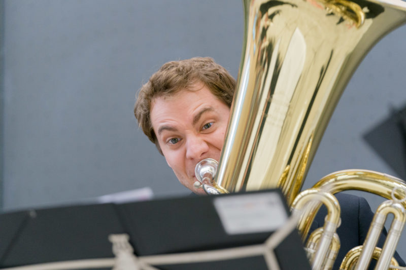 Editorial photography as event photography and fair photography: At an anniversary event of a university, a member of the university orchestra plays with inflated cheeks on the tuba.