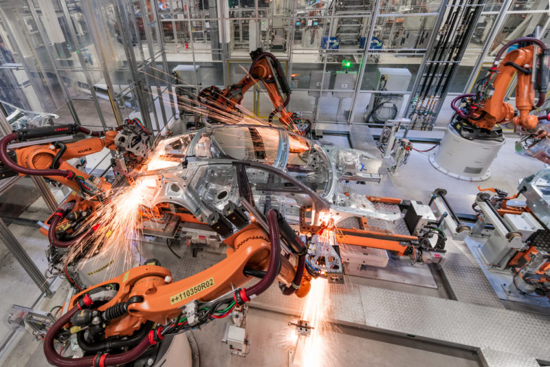 Industrial photography: Welding robots are working on a vehicle body in a large automobile factory.