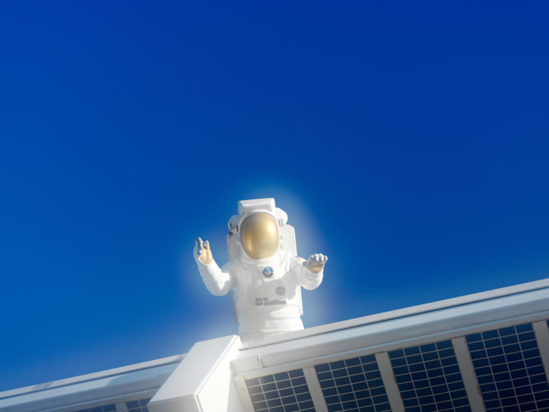 editorial photography: The doll of an astronaut is above the entrance to the Kennedy Space Center in the blue sky.