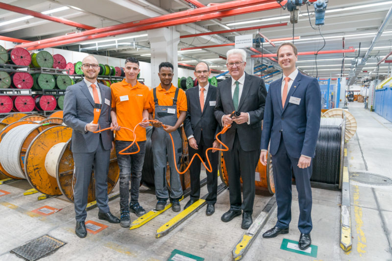 Event photography, editorial photography: Winfried Kretschmann, Prime Minister of Baden-Württemberg and company representative including two refugees who are training here.posing with an electric car charging cable in their hand while visiting the company Lapp Kabel in Stuttgart for a press photo.