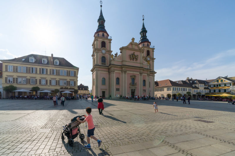 Landscape photogaphy: The market place of the Swabian city of Ludwigsburg with the baroque protestant city church. In the foreground a father with playing children.