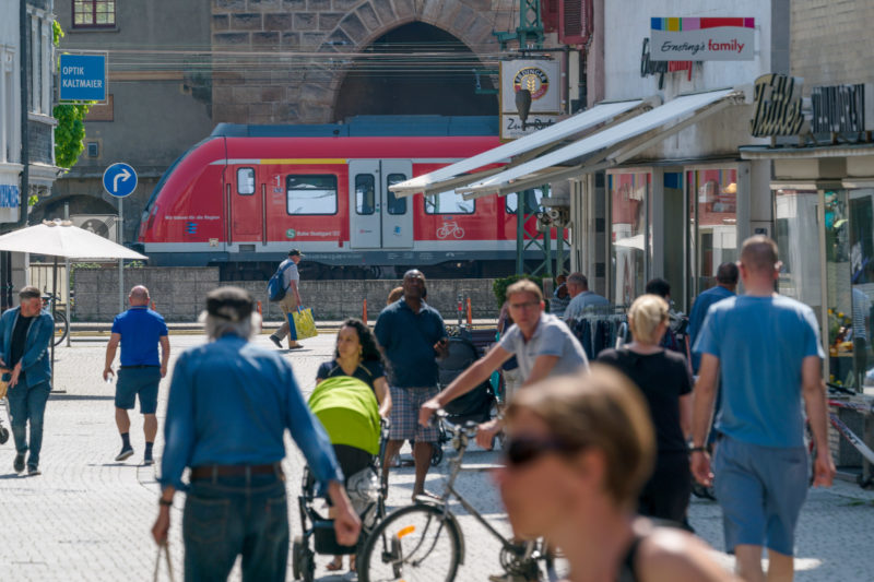 Landscape photogaphy: A typical urban scene with passers-by, far-riding bicyclists, a train and shops in a medium-sized German town.