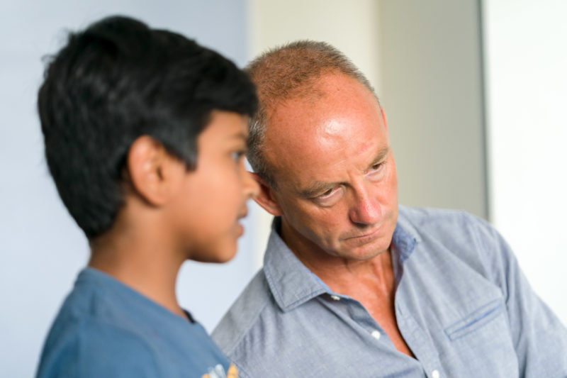 Editorial photography: A teacher at work: Editorial photography, subject learning and education: A teacher listens attentively and confidentially to one of his students during a break in class.